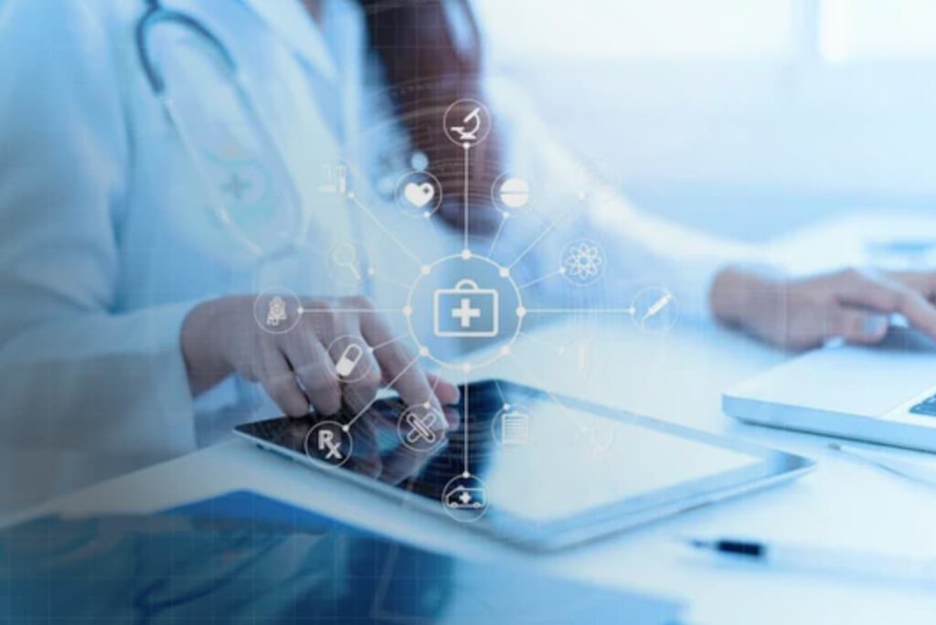 healthcare practitioner at desk using tablet and computer